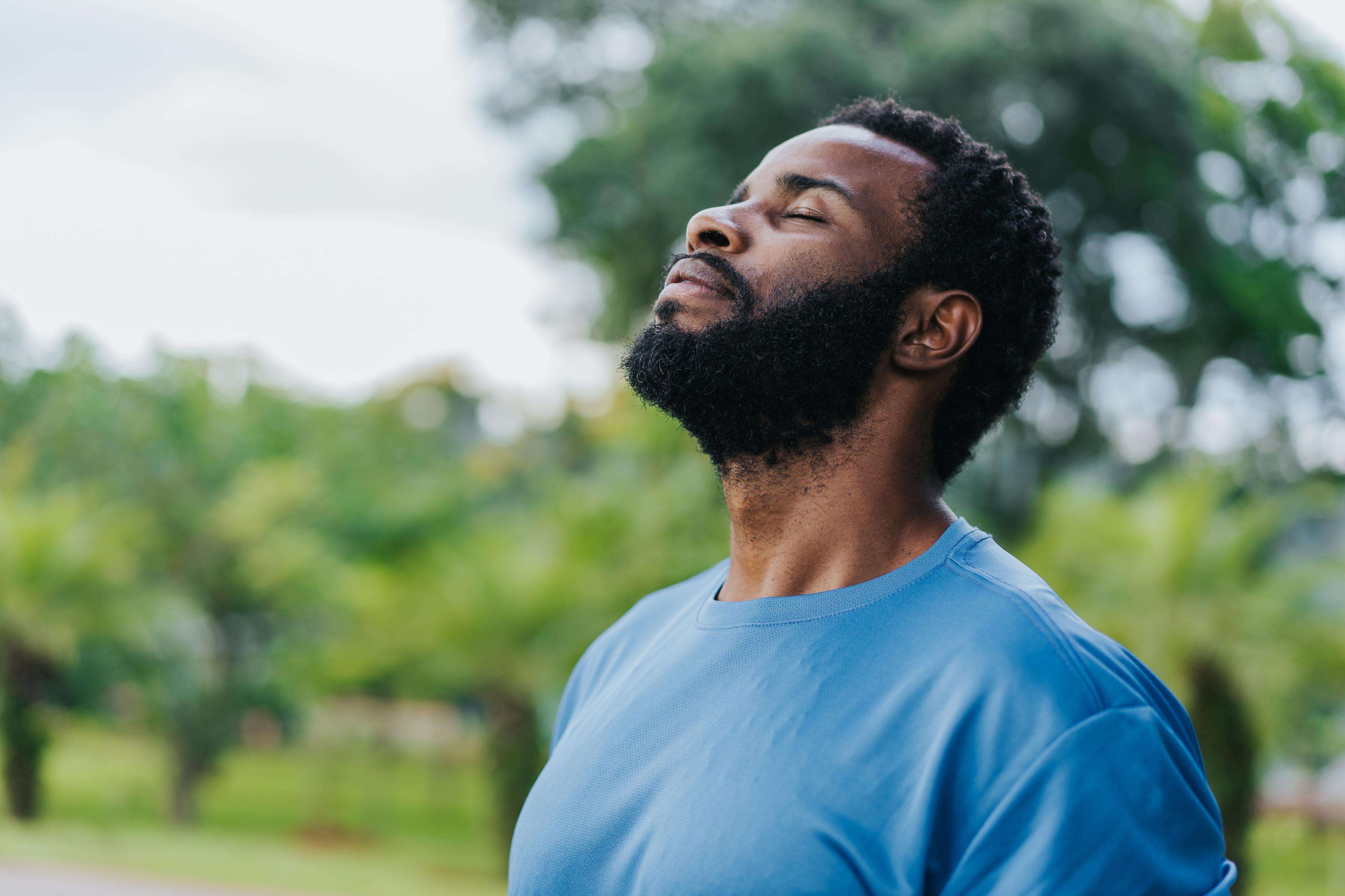 Person with eyes closed breathing deeply outdoors